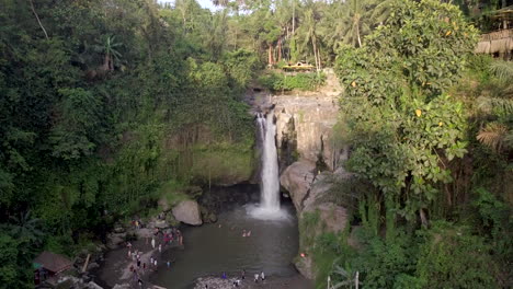 aerial-view-of-tourists-enjoying-the-tropical-Tegenungan-waterfall-in-the-luxuriant-rainforest,-Bali
