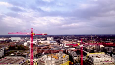 Movimiento-Descendente-Aéreo-Que-Muestra-Grullas-Rojas-Elevándose-Sobre-Una-Zona-Residencial