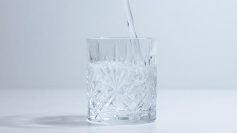 clear-liquid-water-being-poured-into-embossed-rocks-drinking-glass