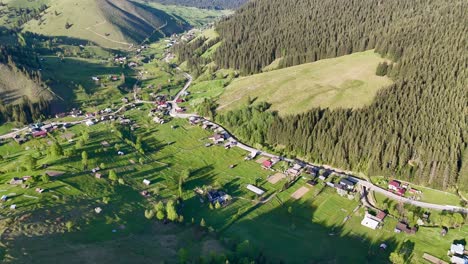 Aerial-footage-of-Slatioara-village-in-Romania,-showcasing-its-simple-houses-and-the-village-nestled-amidst-hills-covered-with-trees