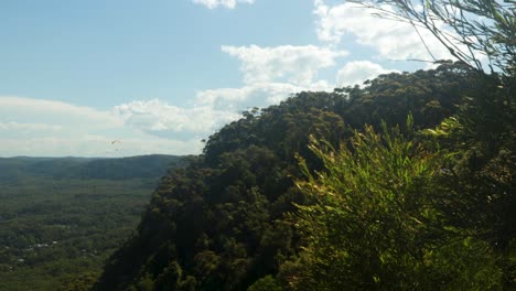 Mountain-top-view-of-mountains,-town-and-paraglider-in-the-distance