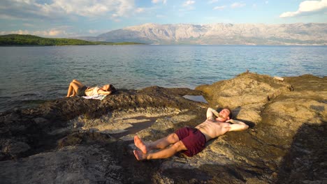 Paar-Touristen-Sonnenbaden-Auf-Den-Felsen-Am-Strand-Von-Sumartin-Auf-Der-Insel-Brac,-Kroatien,-Ca.-Juni-2016