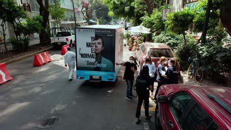 above-wide-angle-establishing-shot-of-truck-at-street-in-lush-green-town-at-day