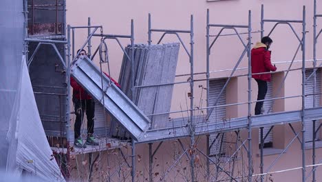 Two-men-dismantling-scaffolding-on-building