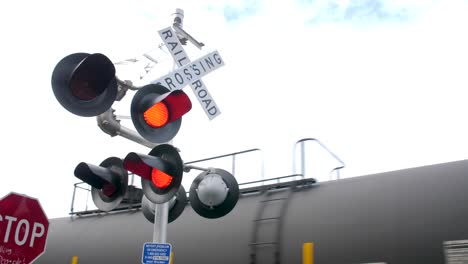Active-railroad-crossing-sign-with-train-passing-in-the-background