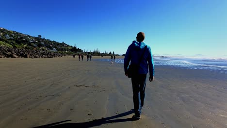 A-man-taking-a-walk-on-a-beach-on-a-sunny-winters-day