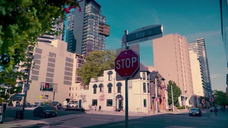 Panorámica-Lenta-De-La-Señal-De-Stop-En-Primer-Plano-Con-La-Intersección-De-Bloor-Y-Bay-Street-Al-Fondo