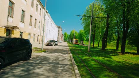 Street-with-white-old-houses-in-city-with-parked-cars-and-tramway-travel