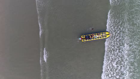 Zenith-Aerial-drone-view-of-banana-boat-getting-in-to-the-water-with-people-pushing