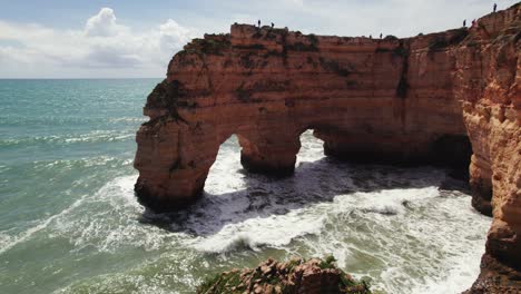 Dos-Arcos-Naturales-Con-Pilas-De-Mar-Y-Olas-Rompiendo-En-Los-Pintorescos-Acantilados-De-Estrada-Da-Caramujeira-Drone-Aéreo-4k-Estableciendo-Tomas-En-La-Región-Del-Algarve-De-Portugal