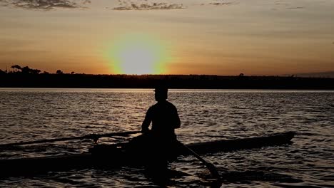 Closeup-silhouette-of-male-athlete-in-rowing-boat-on-colourful-sunset-lake-training