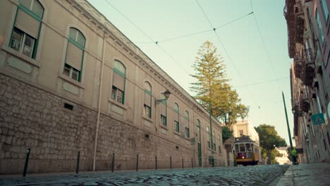 Lisbon-Tram-28-passing-by-at-Alfama-neigborhood-stone-pavement-during-sunrise-4K-16:9-Low-Angle