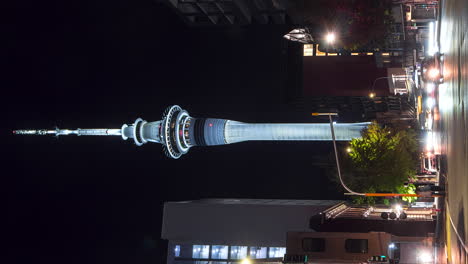 Sky-Tower-in-Auckland,-New-Zealand,-illuminated-at-night,-vertical-timelapse