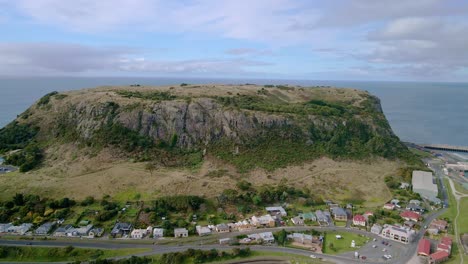 Rising-tilt-aerial-of-The-Nut-mountain-with-Stanley-town-houses-in-foreground,-Tasmania,-Australia