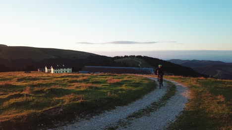 Mountainbiker-Fahren-Den-Berg-Hinauf-Auf-Makadam-Straße-Bei-Sonnenuntergang