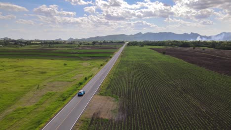 An-Aerial-Drone-Shot-of-a-Blue-Toyota-CHR-Vehicle-Driving-Along-a-Straight-Road-in-the-Countryside-of-Lopburi,-Thailand