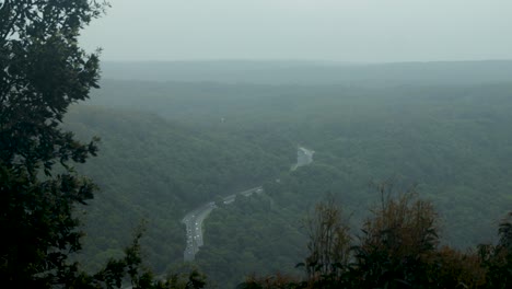 Vista-Lejana-De-La-Carretera-En-El-Bosque-En-Un-Día-Brumoso-Desde-La-Montaña-Pov