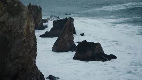 Cinematic-shot-of-waves-hitting-sharp-jagged-rocks-on-the-coastline