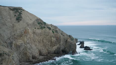Overview-shot-of-waves-hitting-against-a-steep-cliff-outside-of-San-Francisco