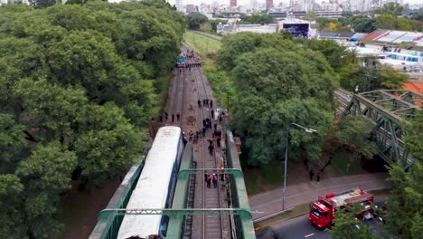 Emergency-staff-by-crashed-train-on-tracks-in-Argentina,-forward-drone