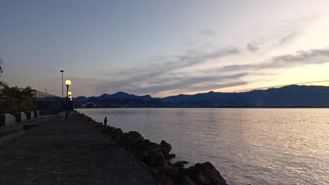 Slow-motion-shot-of-fishermen's-silhouettes-on-the-shores-of-the-Mamuju-ocean-at-dusk