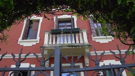 Scenic-exterior-view-through-gate-with-plants-and-balcony-from-italian-architectural-house