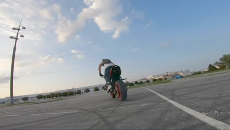 Stunt-biker-doing-a-burn-out-in-a-parking-lot,-filmed-with-an-FPV-drone