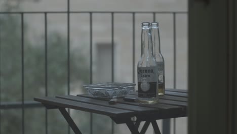 Two-Corona-beer-bottles-with-two-lighters-and-an-ashtray-on-a-wood-table-at-a-Jerusalem-apartment-balcony