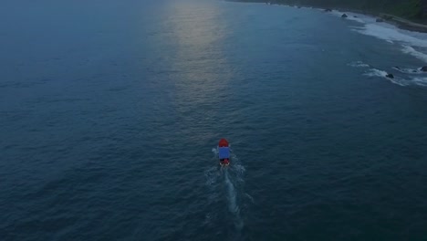 Aerial-view-of-a-blue-and-orange-boat-cruising-a-calm-green-caribbean-sea