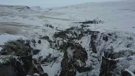 Paisaje-Islandés-Cubierto-De-Nieve-Y-Hielo-En-Una-Formación-Rocosa-Gorje,-Disparo-Aéreo-De-Drones,-Islandia