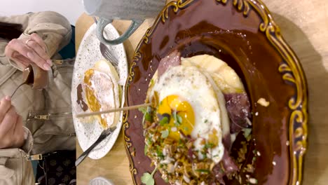 Weibliche-Hand-Gießt-Schokolade-über-Pfannkuchen-In-Einem-Restaurant