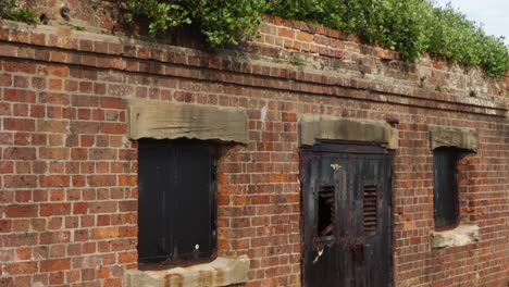 Tilt-down-reveal-of-abandoned-brick-bunker-under-grass-handheld