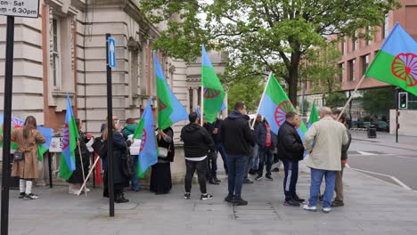 A-group-of-people-hold-blue-and-green-Roma-flags-displaying-the-red-cartwheel-symbol-during-a-protest-on-International-Romani-Day