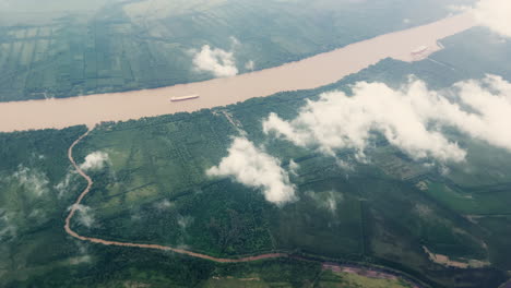 Toma-Aérea-De-Un-Río-En-Argentina-Con-Barcos-De-Carga,-Nubes-Y-Bosque