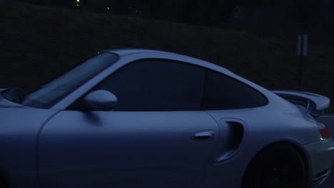 Un-Hermoso-Auto-Deportivo-Porsche-Gris-Conduciendo-Por-La-Autopista-De-Nannestad,-Noruega-Por-La-Noche---Toma-En-Movimiento