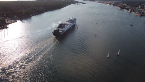 Ferry-vessel-leaving-seaport-of-Klaipeda-city,-drone-follow-up-view