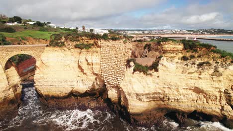 Aerial-4k-drone-circle-view-of-man-made-arch-at-beach-estudantes-in-Lagos,-the-algarve-region-of-Portugal