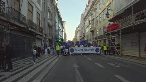 People-marching-in-a-pro-life-rally-on-a-sunny-day-in-Lisbon,-wide-angle-shot