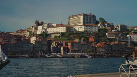 Ribeira-in-Porto,-Portugal-filmed-near-sunset-on-a-vintage-lens-with-the-River-Douro-in-the-foreground-and-old-city-in-the-background-at-4k