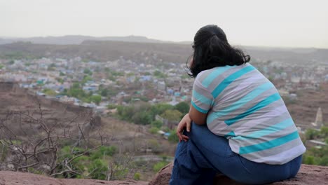 Aislar-A-Una-Chica-Viendo-El-Paisaje-De-La-Ciudad-En-La-Cima-De-La-Montaña-Con-Un-Cielo-Espectacular-Al-Atardecer.-El-Vídeo-Se-Toma-En-Mehrangarh-Jodhpur-Rajasthan-India.