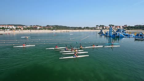 Large-group-of-boys-and-girls-equipped-with-life-jackets-practice-canoeing-on-the-circuit-supervised-by-their-water-sports-teacher-on-the-beach,-shooting-tracking