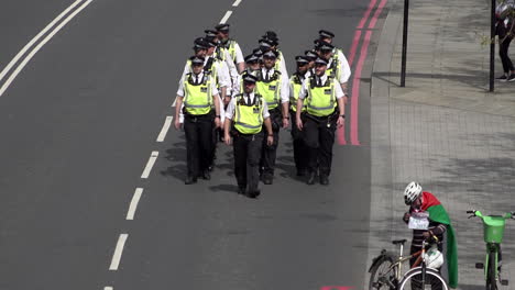 A-unit-of-Metropolitan-police-officer-wearing-yellow-tabards-march-along-a-road-during-a-public-order-event
