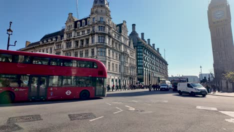 Un-Autobús-Rojo-De-Dos-Pisos-Recorre-La-Plaza-Del-Parlamento,-Londres,-Con-El-Big-Ben-Al-Fondo