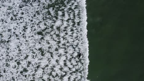 Aerial-view-captures-someone-elegantly-surfing-waves,-epitomizing-the-freeing-spirit-of-leisure-amidst-the-vast-ocean