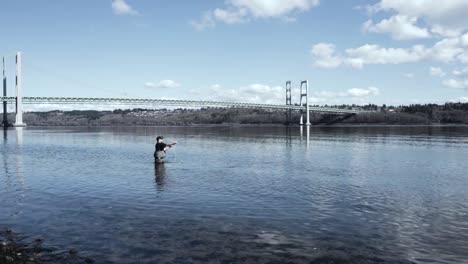 Man-fly-fishing-at-the-Narrows-View-Point-Park-in-Gig-Harbor,-Washington,-Puget-Sound,-Low-Tide