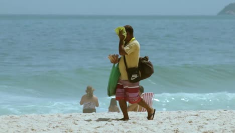 Chico-Trabajando-En-La-Playa-De-Ipanema-Limpiándose-La-Cara-Con-Una-Toalla