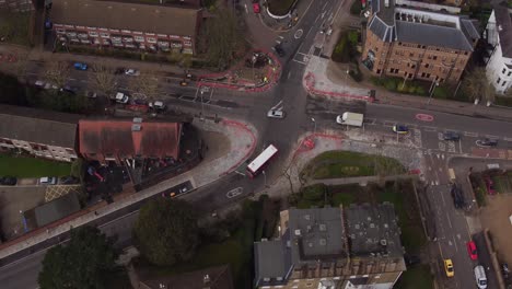 Elevated-tracking-shot-of-a-red-London-bus-traveling-through-Surbiton,-on-the-suburbs-of-London,-UK