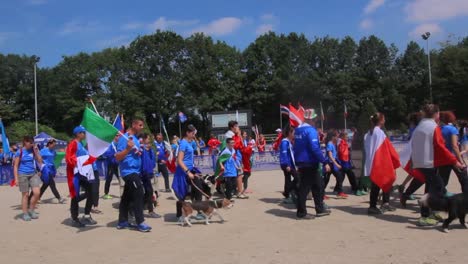 Participantes-De-Diferentes-Países-Ondeando-Banderas-Nacionales-Con-Sus-Perros-En-El-Campeonato-Europeo-Abierto-Juvenil---Competencia-De-Agilidad-En-Holanda---Toma-Panorámica