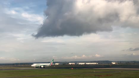 El-Avión-De-Alitalia-Air-Rueda-Lentamente-Por-La-Pista-Fuera-Del-Marco,-El-Camión-A-La-Derecha