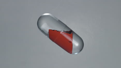 4k-3d-high-quality-graphic-animation-of-a-red-liquid-splashing-around-inside-of-a-medicine-capsule,-on-a-grey-background